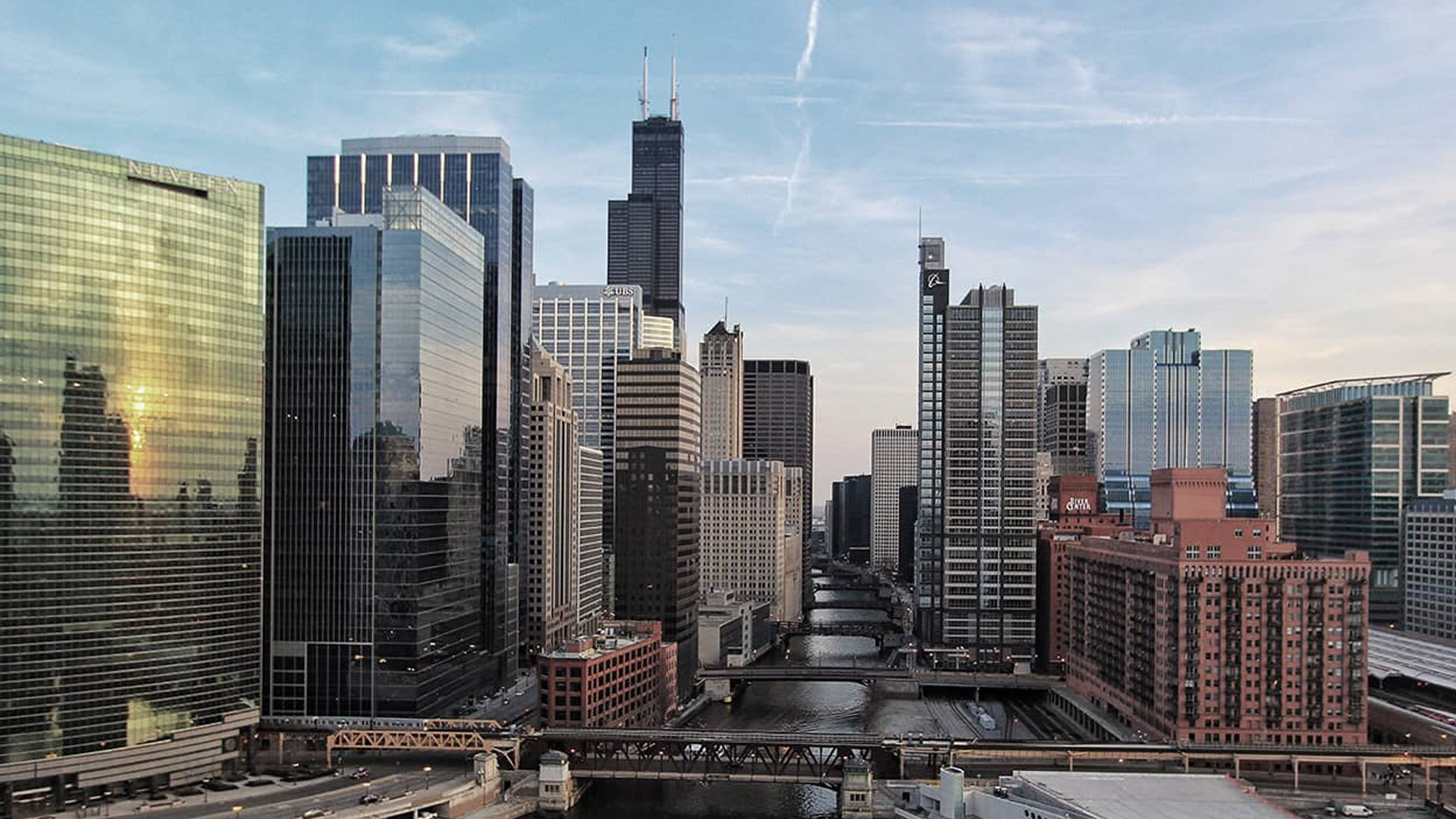 An aerial view of a bustling city skyline with high-rise buildings, including the Chicago skyline with the Willis Tower and other iconic structures.