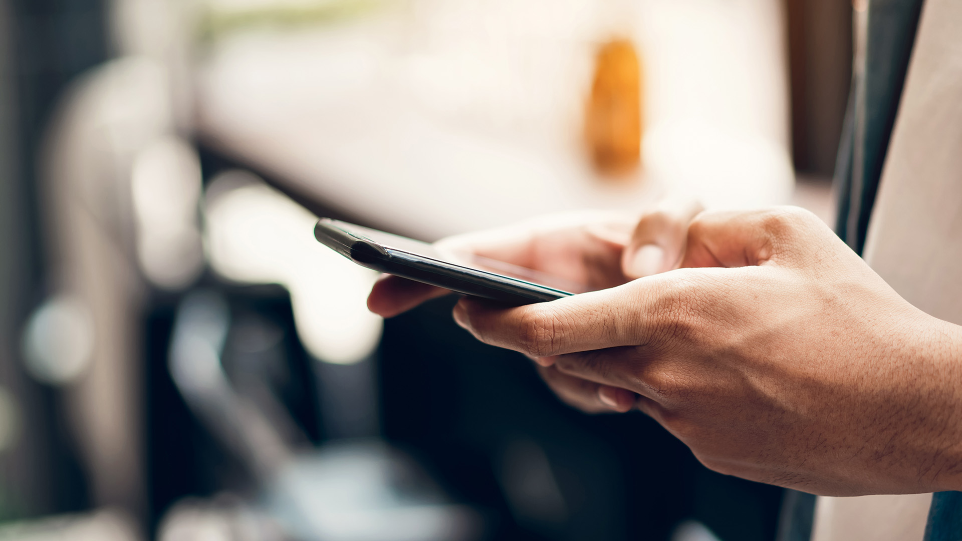 The image shows a person holding a smartphone, which is being used to take a photo. The person appears to be standing in an urban environment with a focus on the phone s screen and their hands.