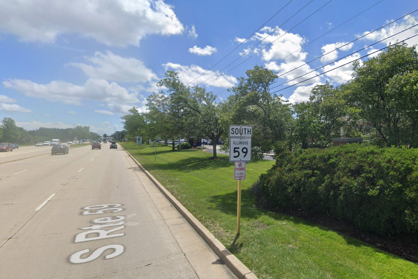 The image shows a street scene with a road sign indicating  S 63  and a directional arrow pointing left, under a blue sky. There are trees in the background, and the setting appears to be during daylight hours.