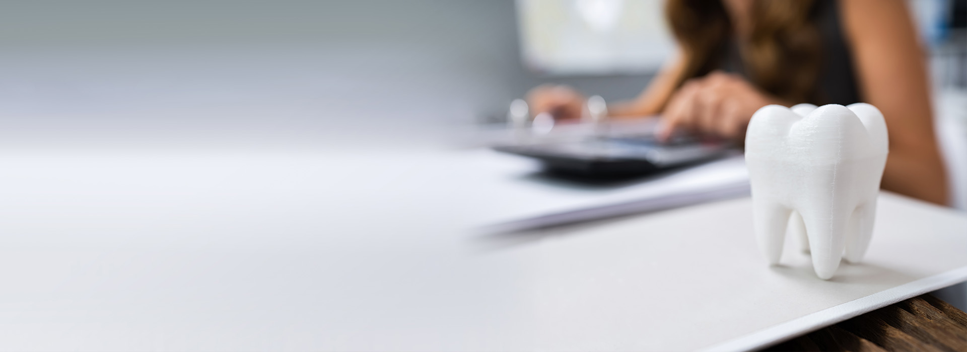 The image shows a person sitting at a desk with a laptop and a toothbrush holder, which appears to contain a toothbrush.