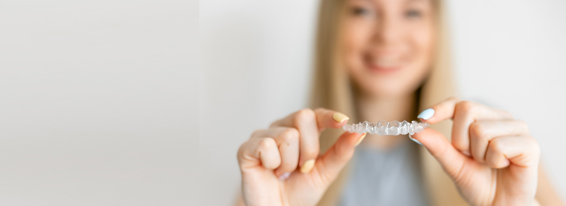 A woman is holding a small, clear object with both hands, smiling at the camera.