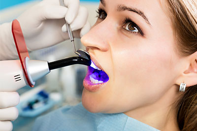 A person receiving a dental implant procedure, with a dentist using a blue device to scan the mouth.