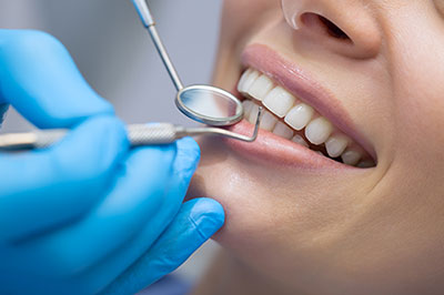 A dental professional using a dental drill on a patient s teeth.