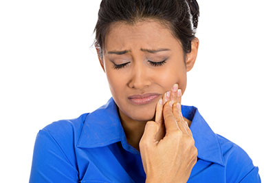 Woman with a concerned expression, touching her face with her hand.