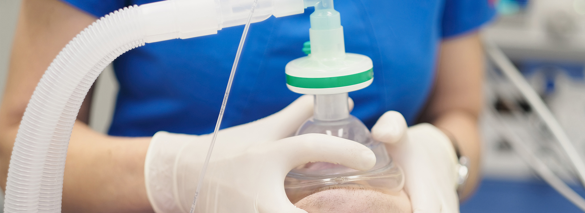 A woman in a white lab coat is handling medical equipment, likely preparing for or conducting a medical procedure.