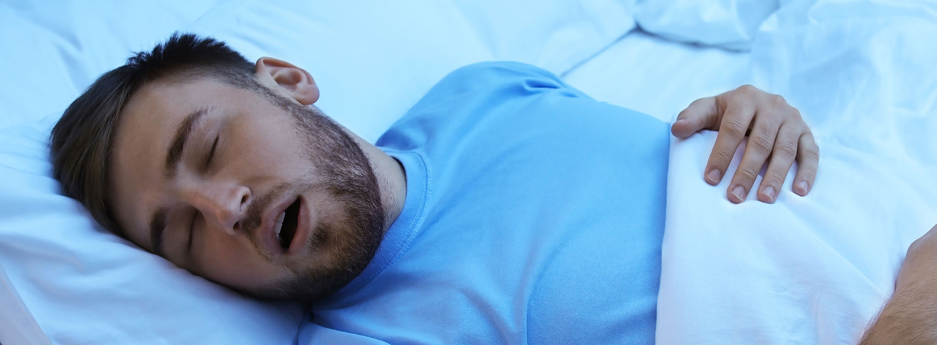 The image is a photograph of a person lying in bed with their eyes closed, appearing to be asleep.